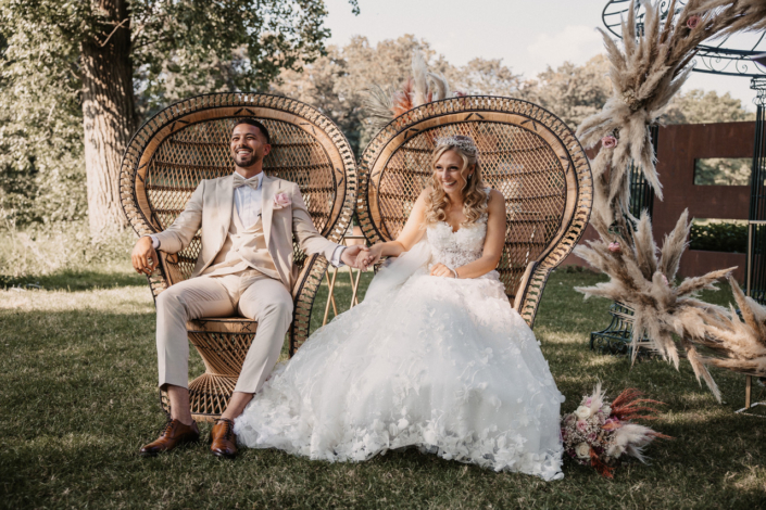 Ein glückliches Hochzeitspaar hält sich während einer Trauzeremonie an der Hand und lacht.