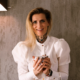 Blonde Frau mit langen Haaren lächelt und hält in der Hand Tasse Kaffee