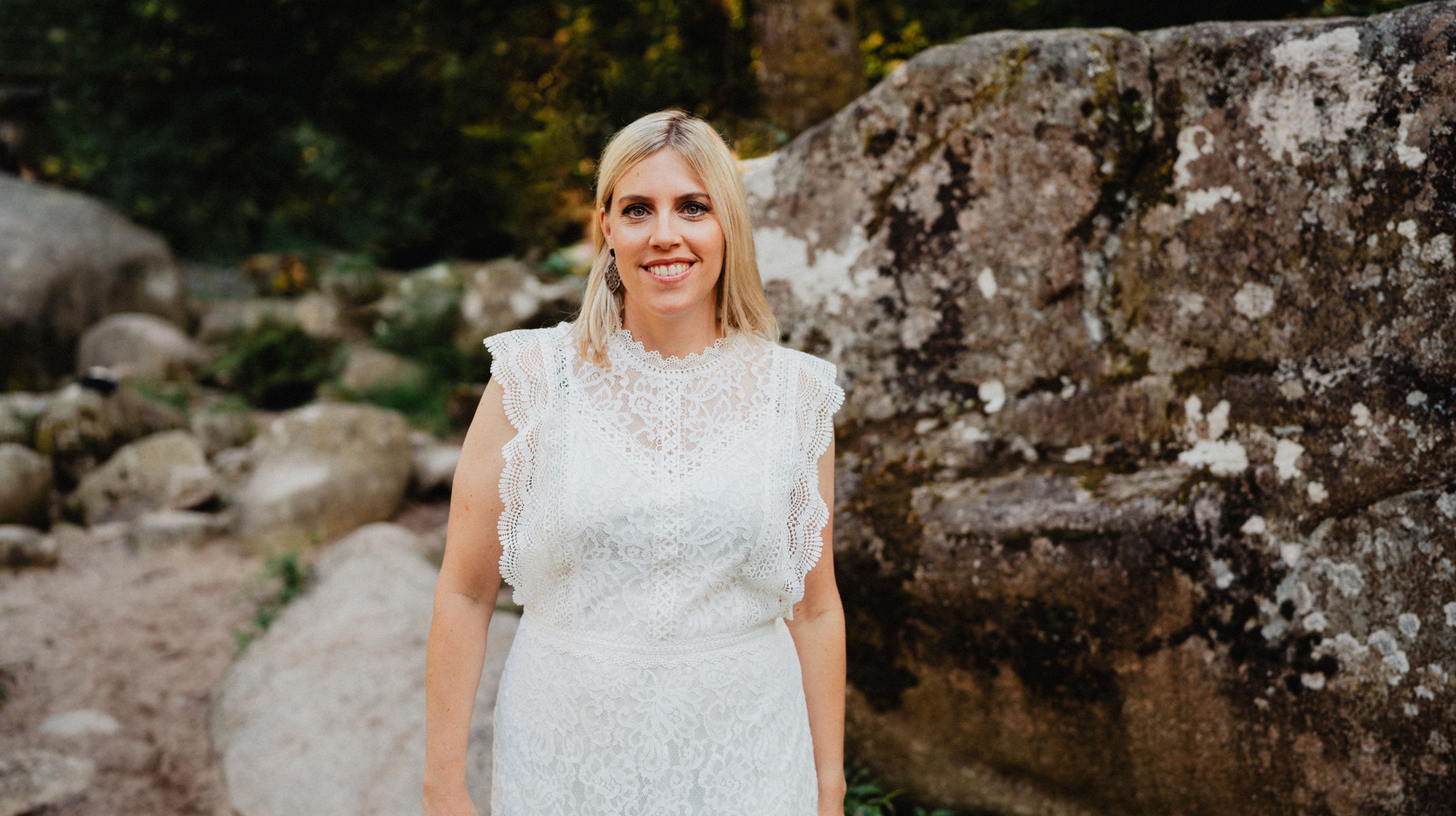 Blonde Frau im weißen Kleid steht in der Natur